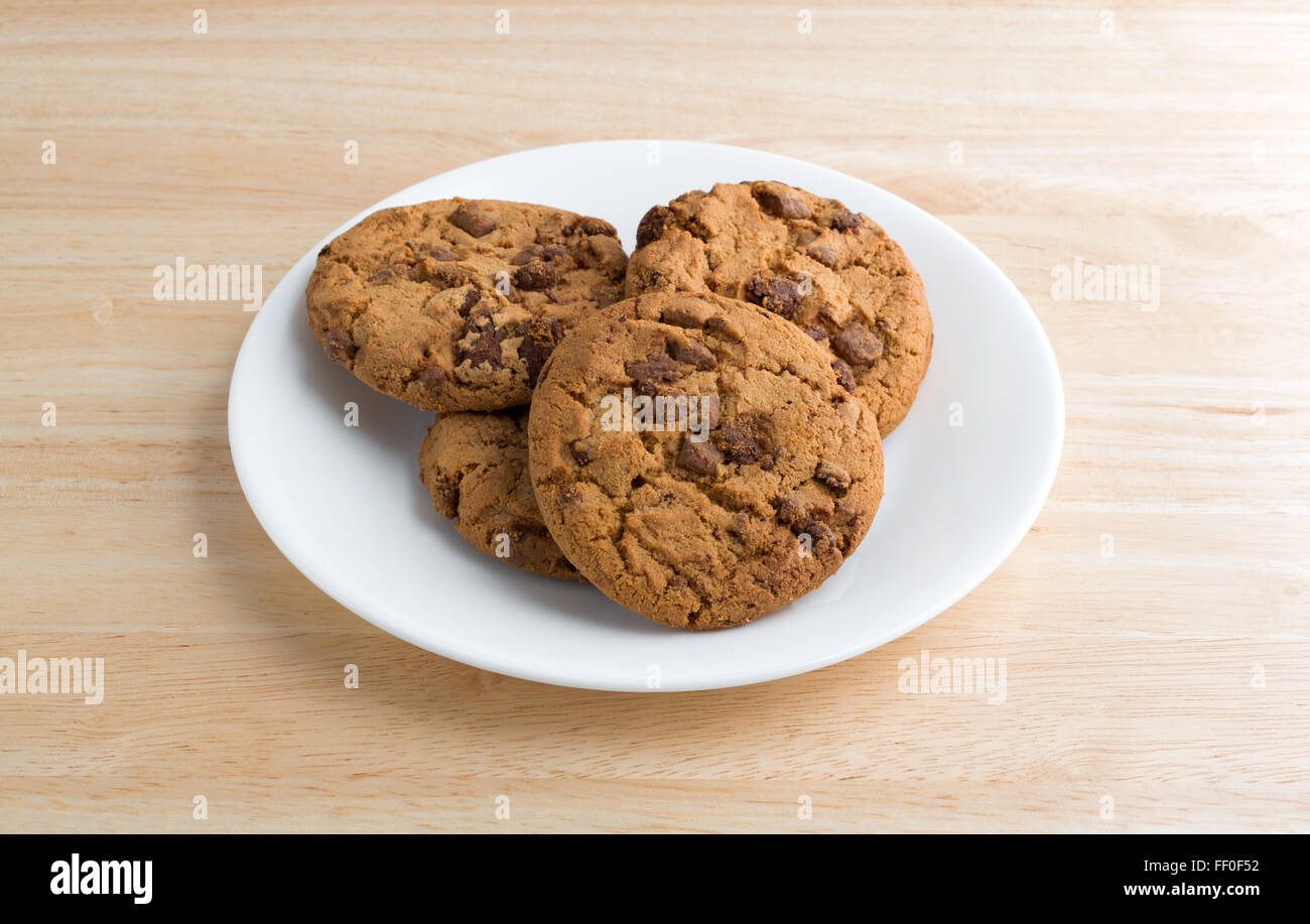 A plate of milk chocolate chip cookies on a wood table top illuminated with natural light. Stock Photo