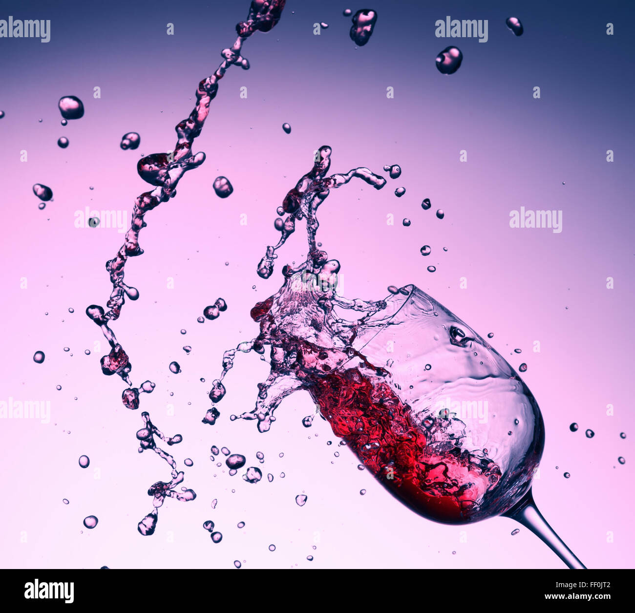red wine splash from glass on purple background. Stock Photo