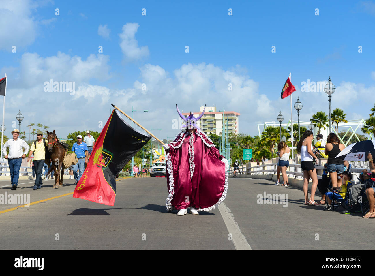 Masked cultural figure vejigante caring the flag of Ponce during the carnival. Ponce, Puerto Rico. February 2016 Stock Photo