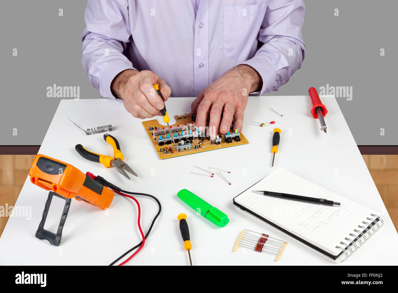 Electronic test engineer using a screwdriver to mount a circuit board switch on his white topped