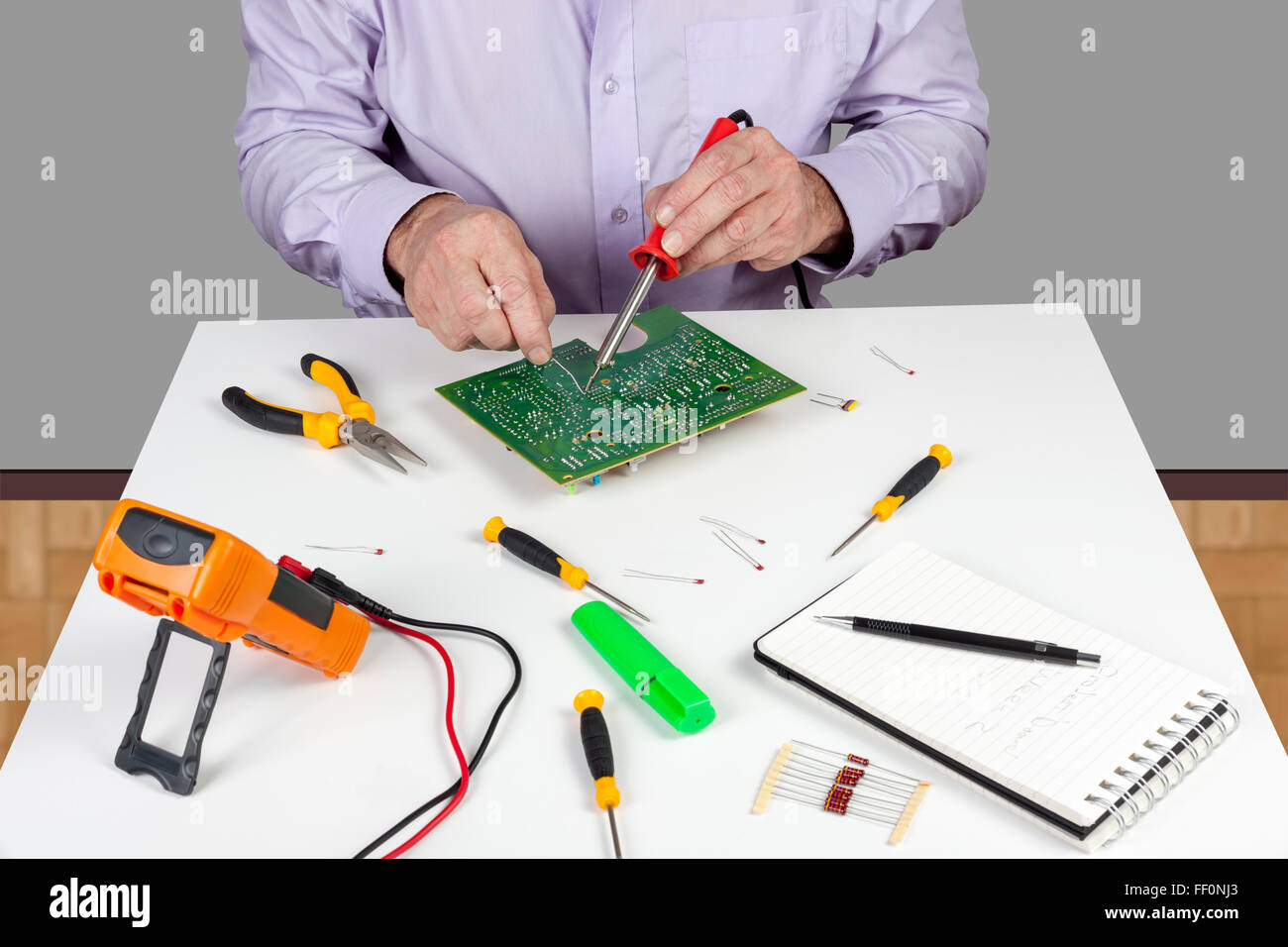 Electronic test engineer using a soldering iron on a printed circuit