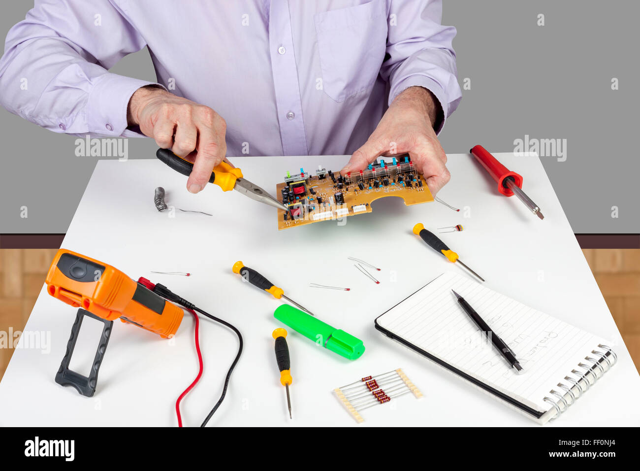 Electronic test engineer using long nose pliers mount component in a