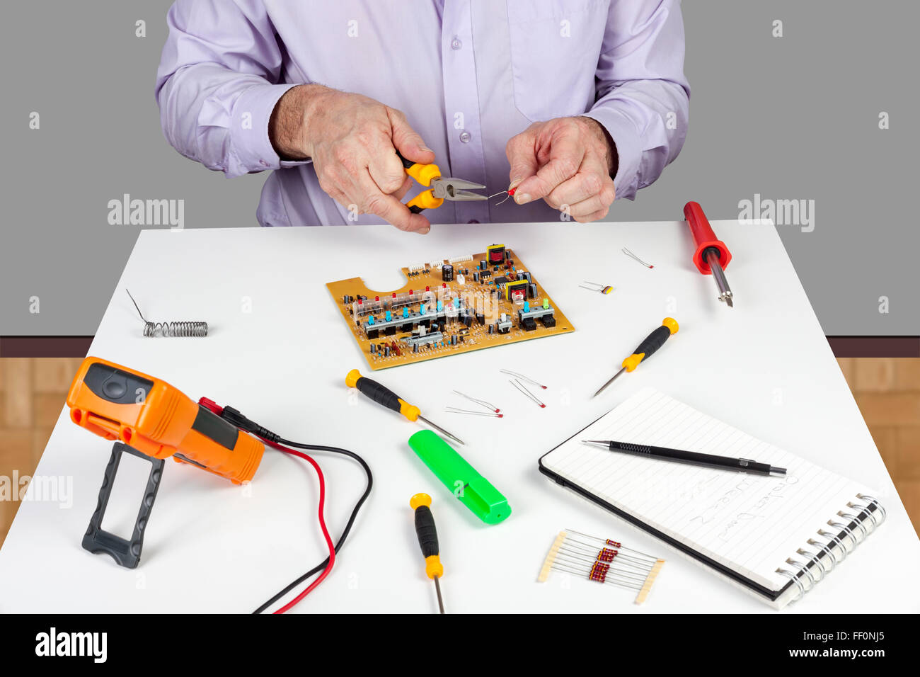 Electronic test engineer using long nose pliers to form a circuit board