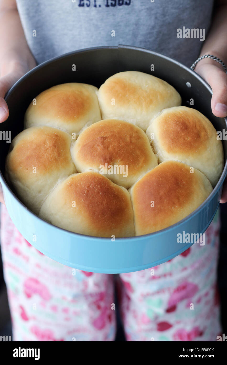 Child hand holding home made baked buns in baking tin Stock Photo