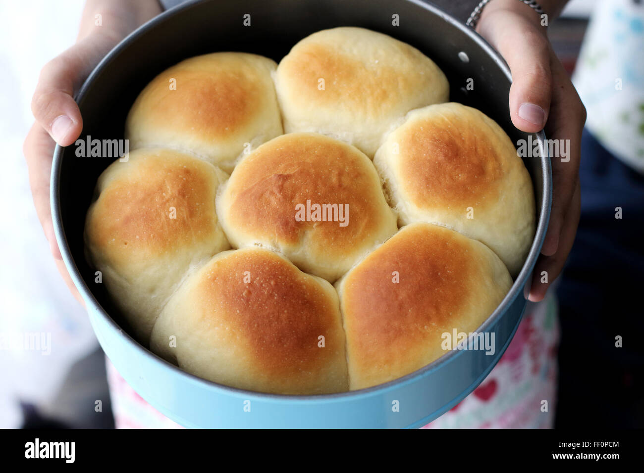 Child hand holding home made baked buns in baking tin Stock Photo