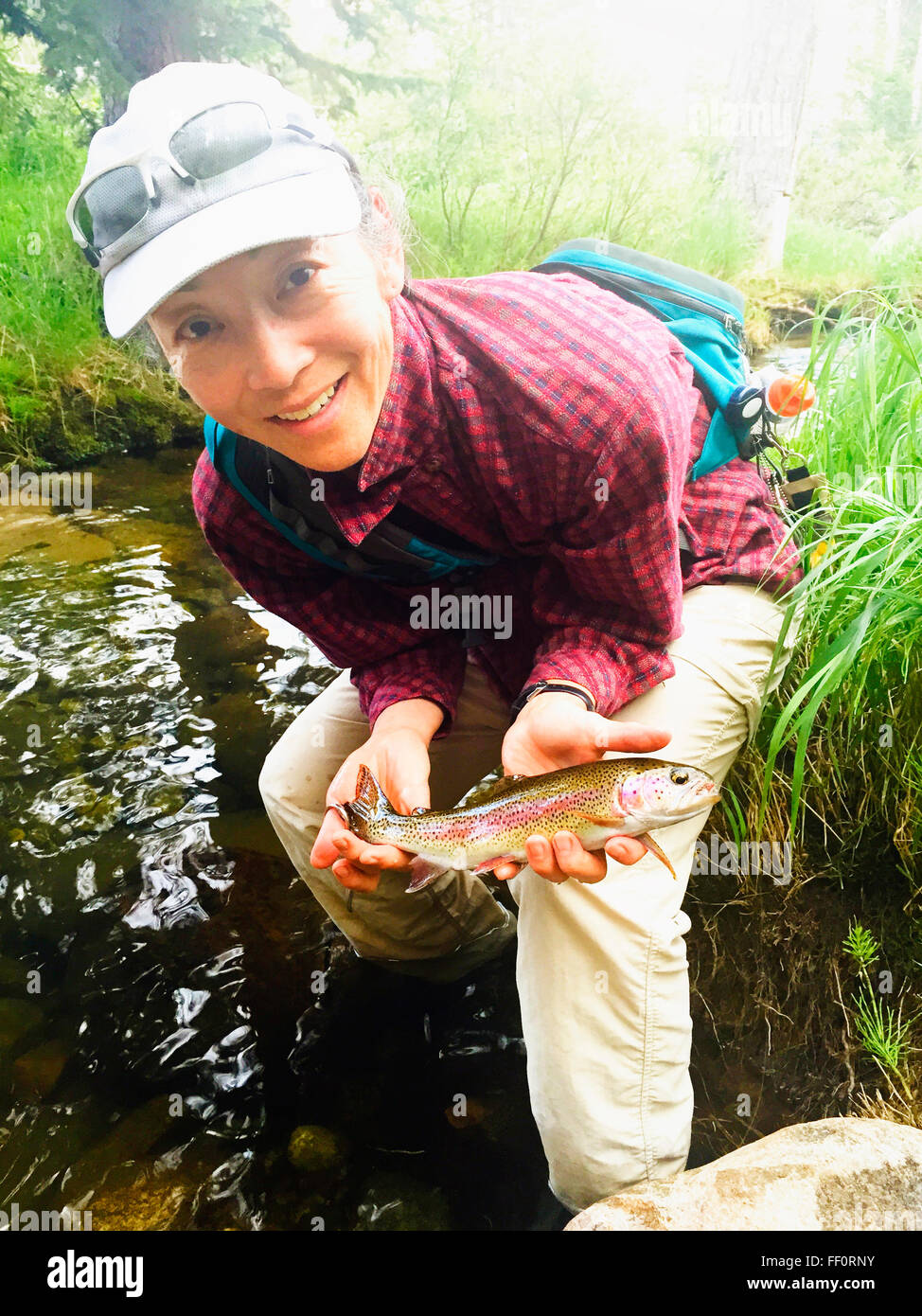 Japanese woman holding fish in stream - Smartphone Captured Stock Image