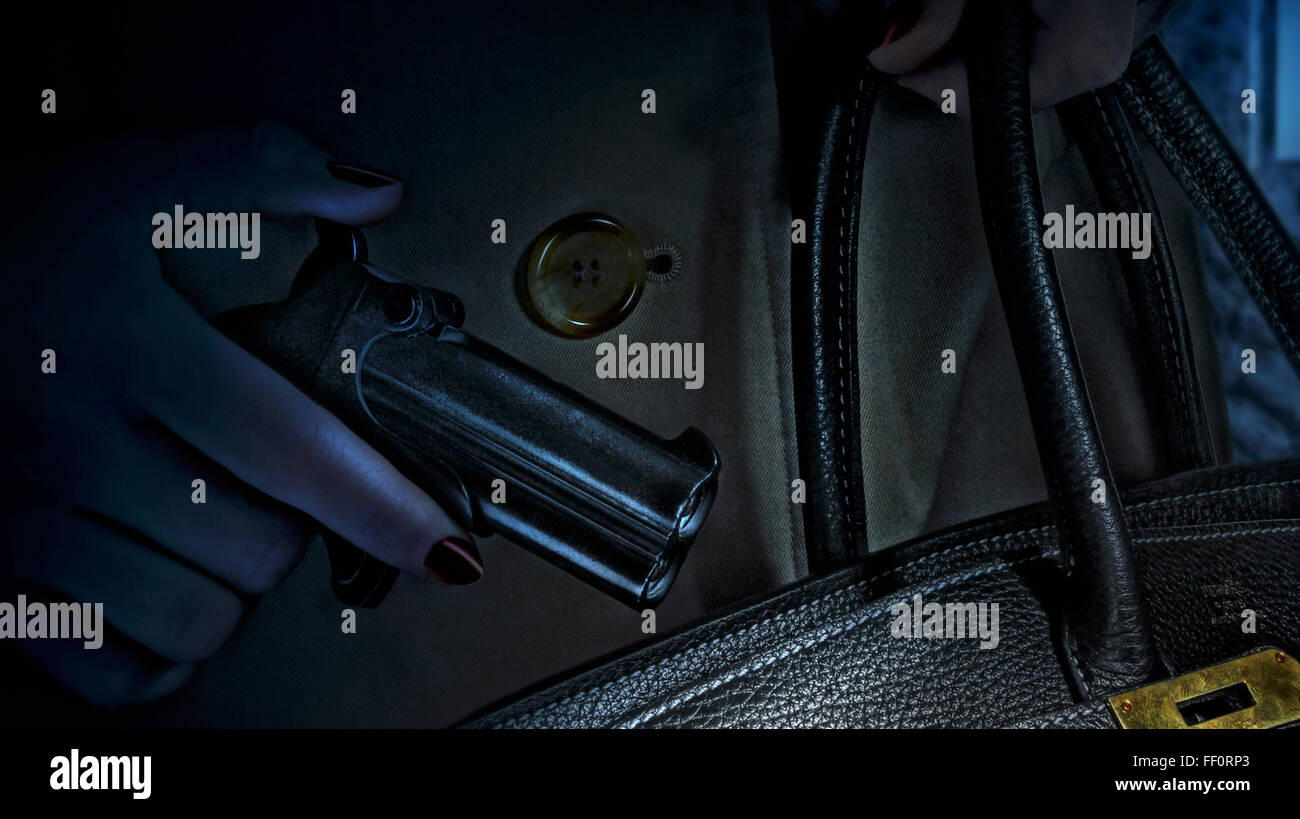 Woman placing gun in purse Stock Photo