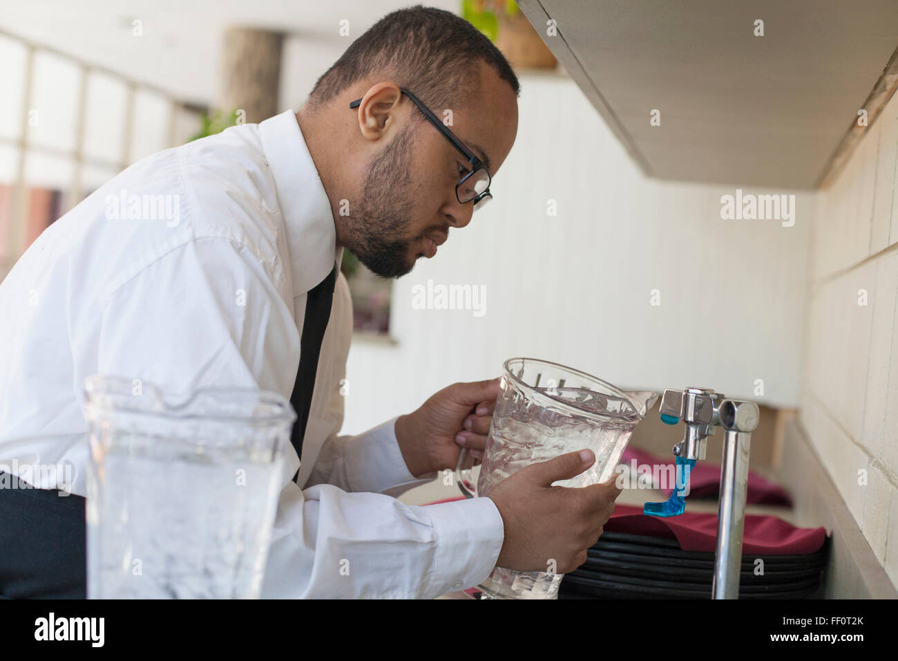 Mixed race server with down syndrome filling pitcher in restaurant Stock Photo