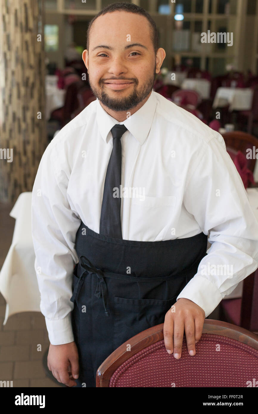 Mixed race server with down syndrome smiling in restaurant Stock Photo
