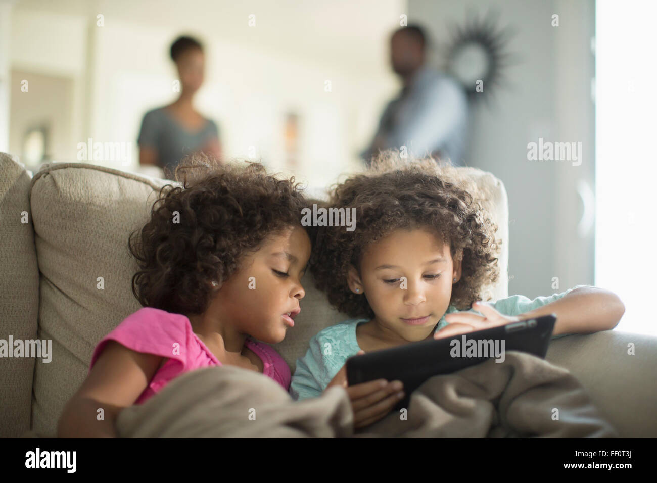 Sisters using digital tablet on sofa Stock Photo - Alamy