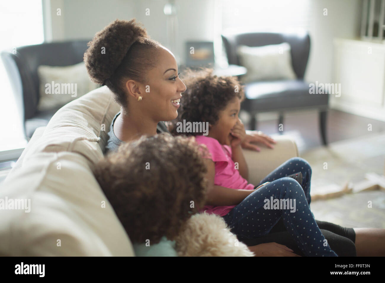 Mother and daughters watching television on sofa Stock Photo