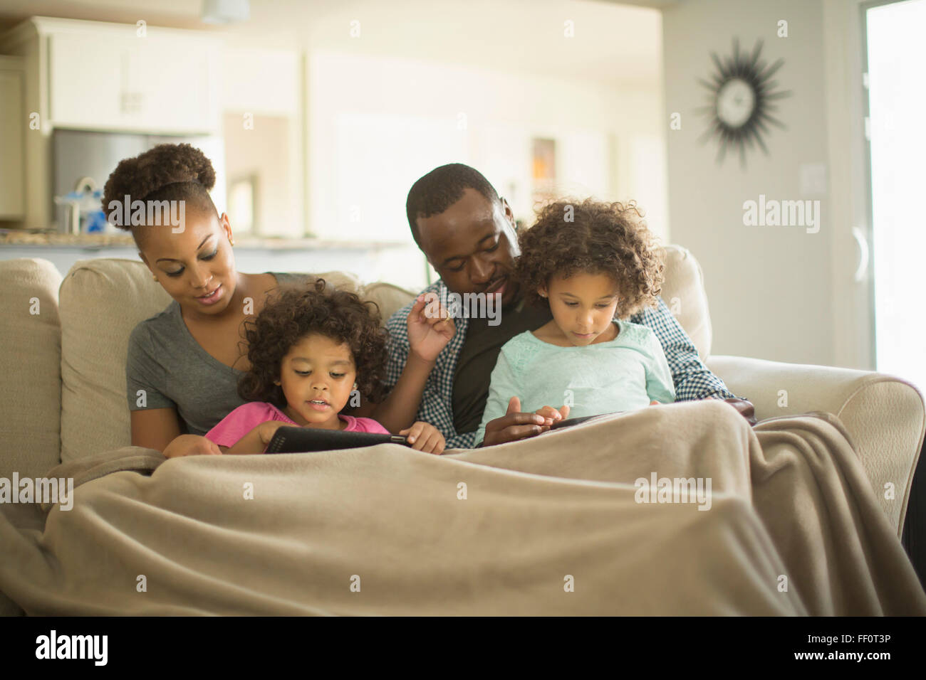 Family using digital tablets on sofa Stock Photo