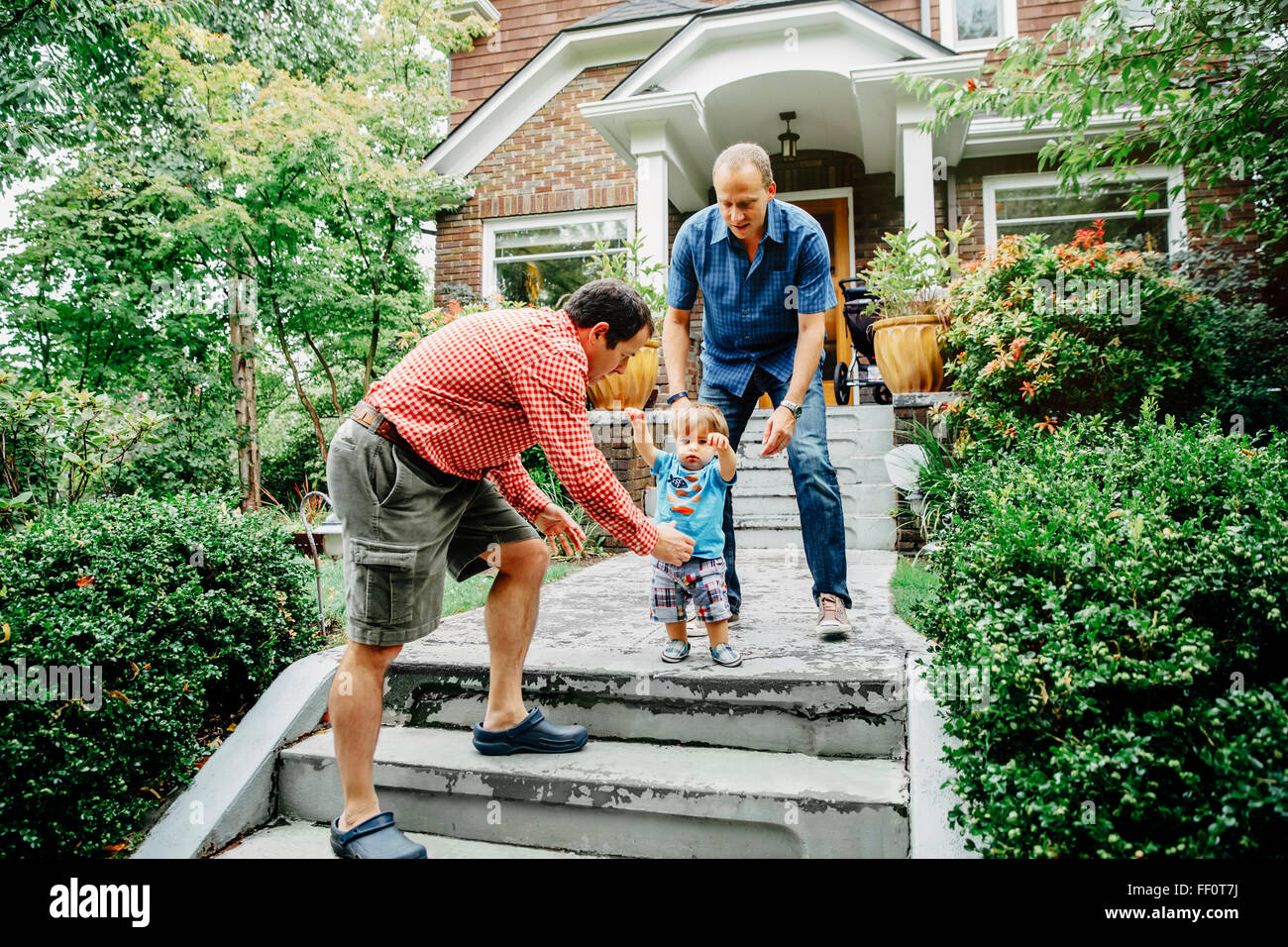 Gay fathers and baby son on steps Stock Photo