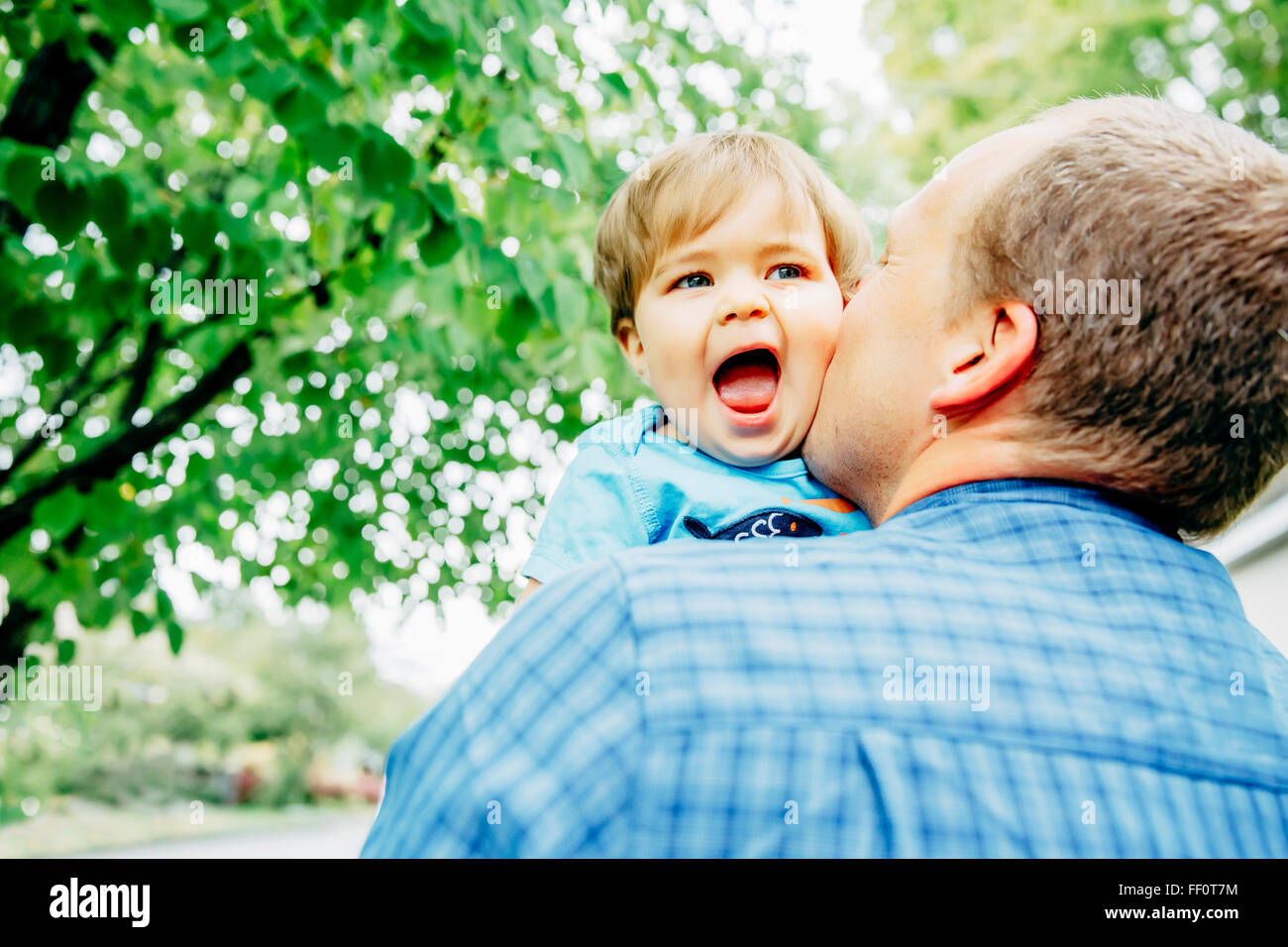 Father kissing cheek of baby son outdoors Stock Photo