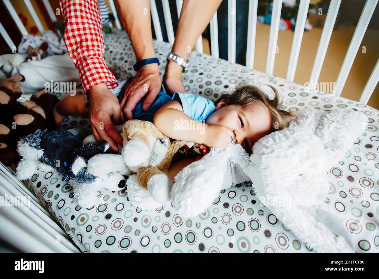 Gay fathers tickling baby son in crib Stock Photo