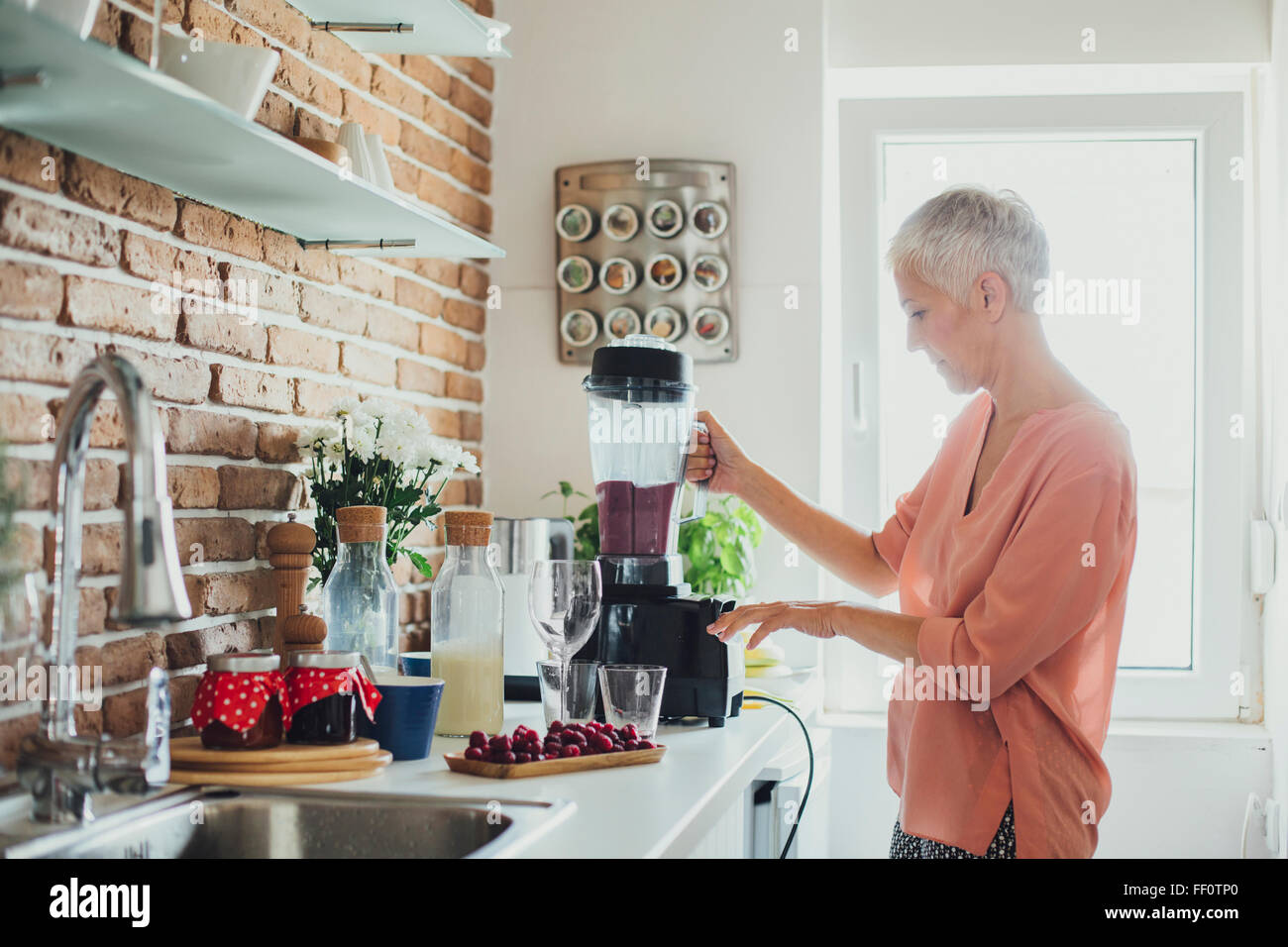 Older Caucasian woman blending smoothie in kitchen Stock Photo