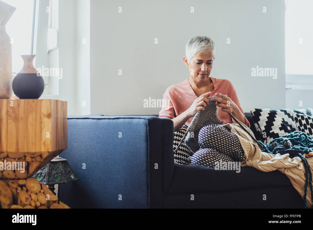 Older Caucasian woman knitting on sofa Stock Photo