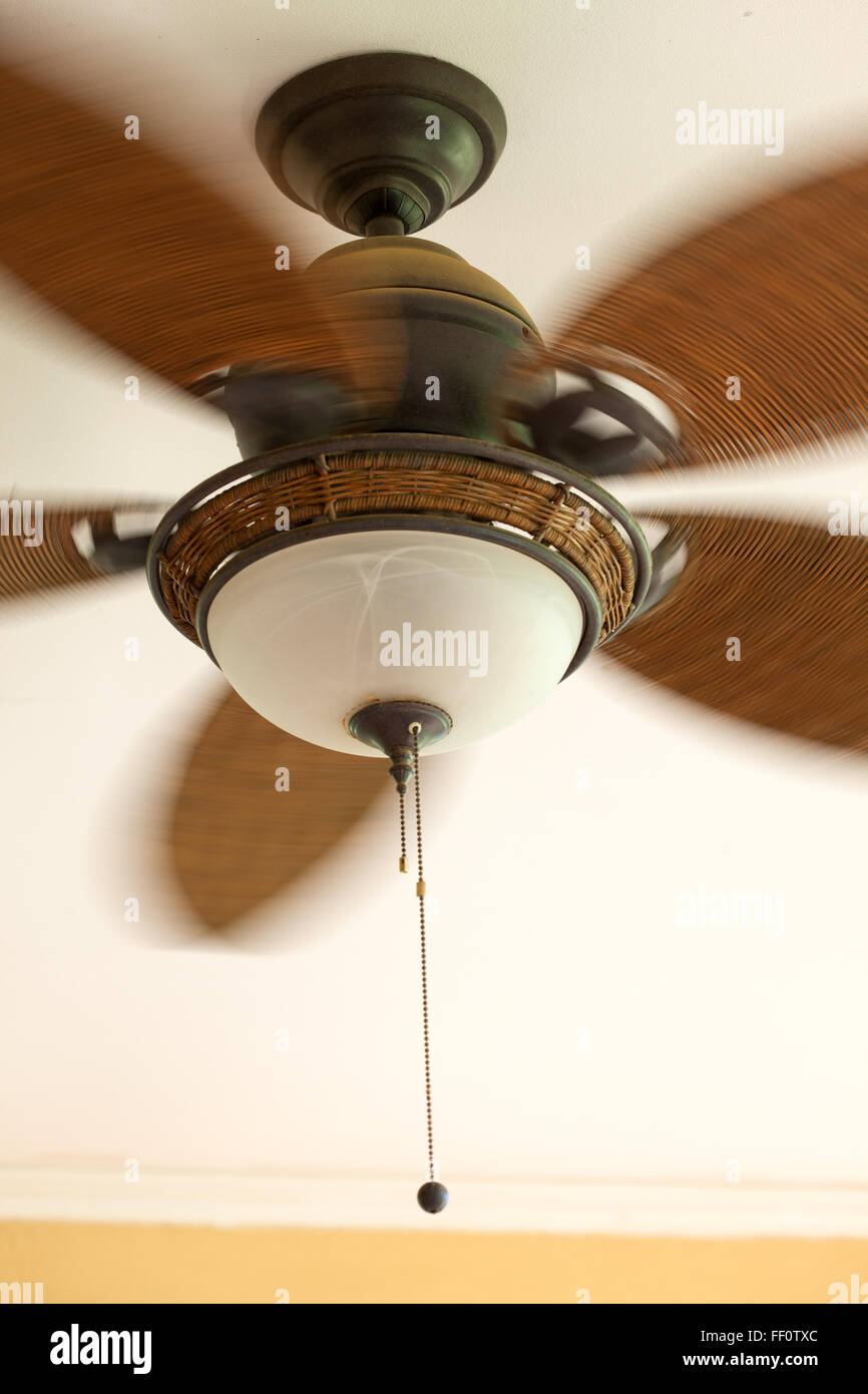 A vintage style fan with wicker blades turning and showing blurred motion. Stock Photo