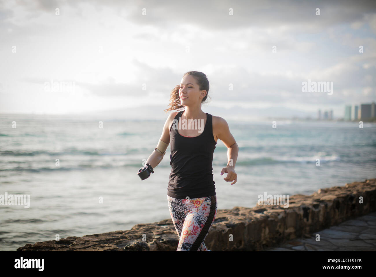 Mixed race amputee athlete jogging on urban waterfront Stock Photo