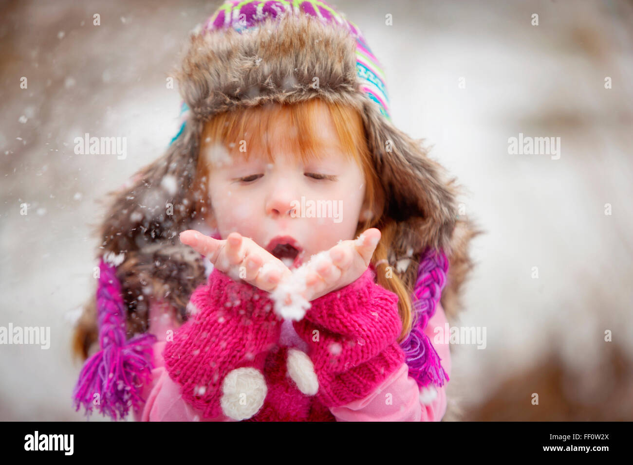 Caucasian girl blowing handful of snow Stock Photo