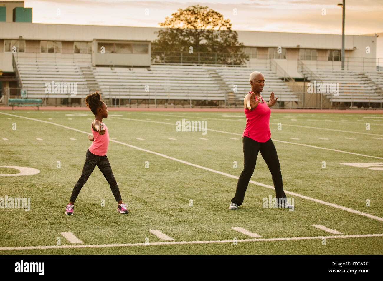 Grandmother and granddaughter exercising on football field Stock Photo
