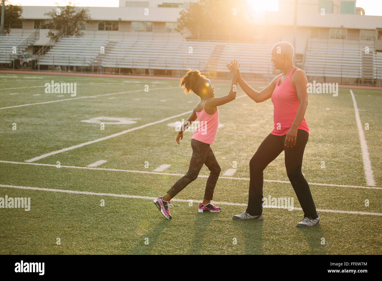 Grandmother and granddaughter high-fiving on football field Stock Photo