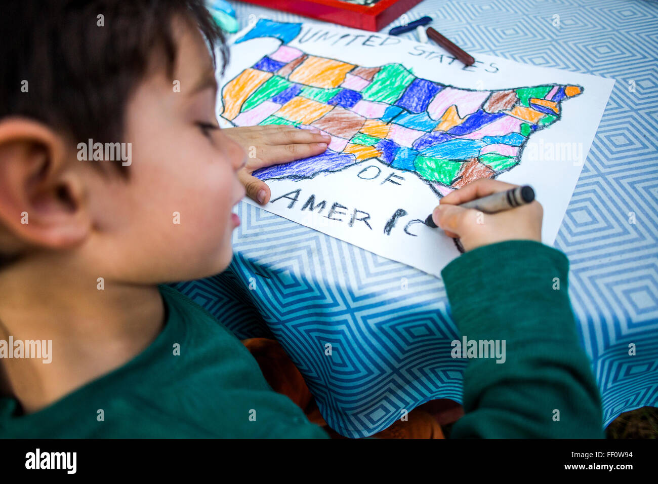 Mixed race boy coloring United States map Stock Photo