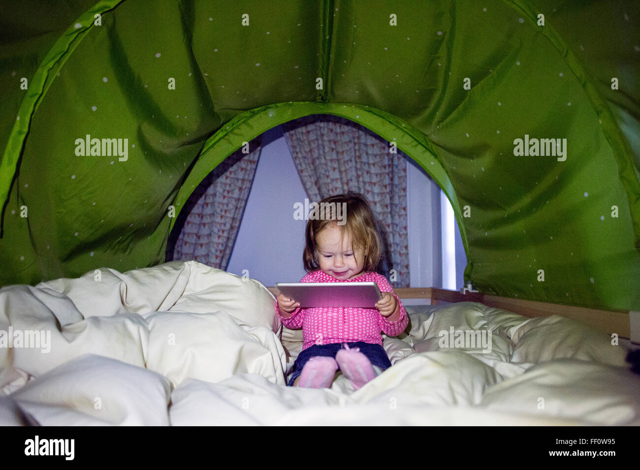 Caucasian baby girl using digital tablet in tent Stock Photo