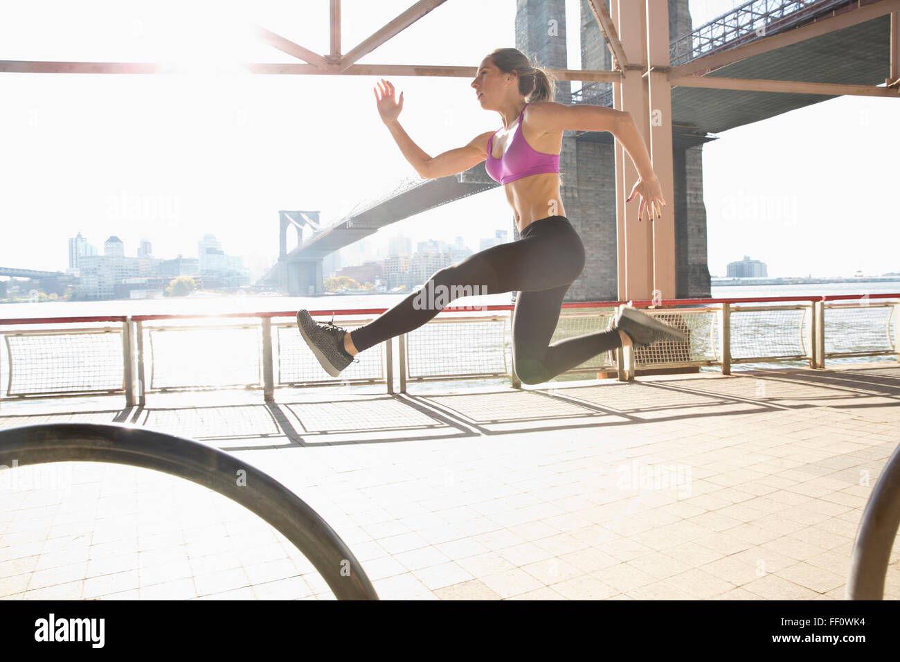 Caucasian runner jumping on waterfront, New York, New York, United States Stock Photo