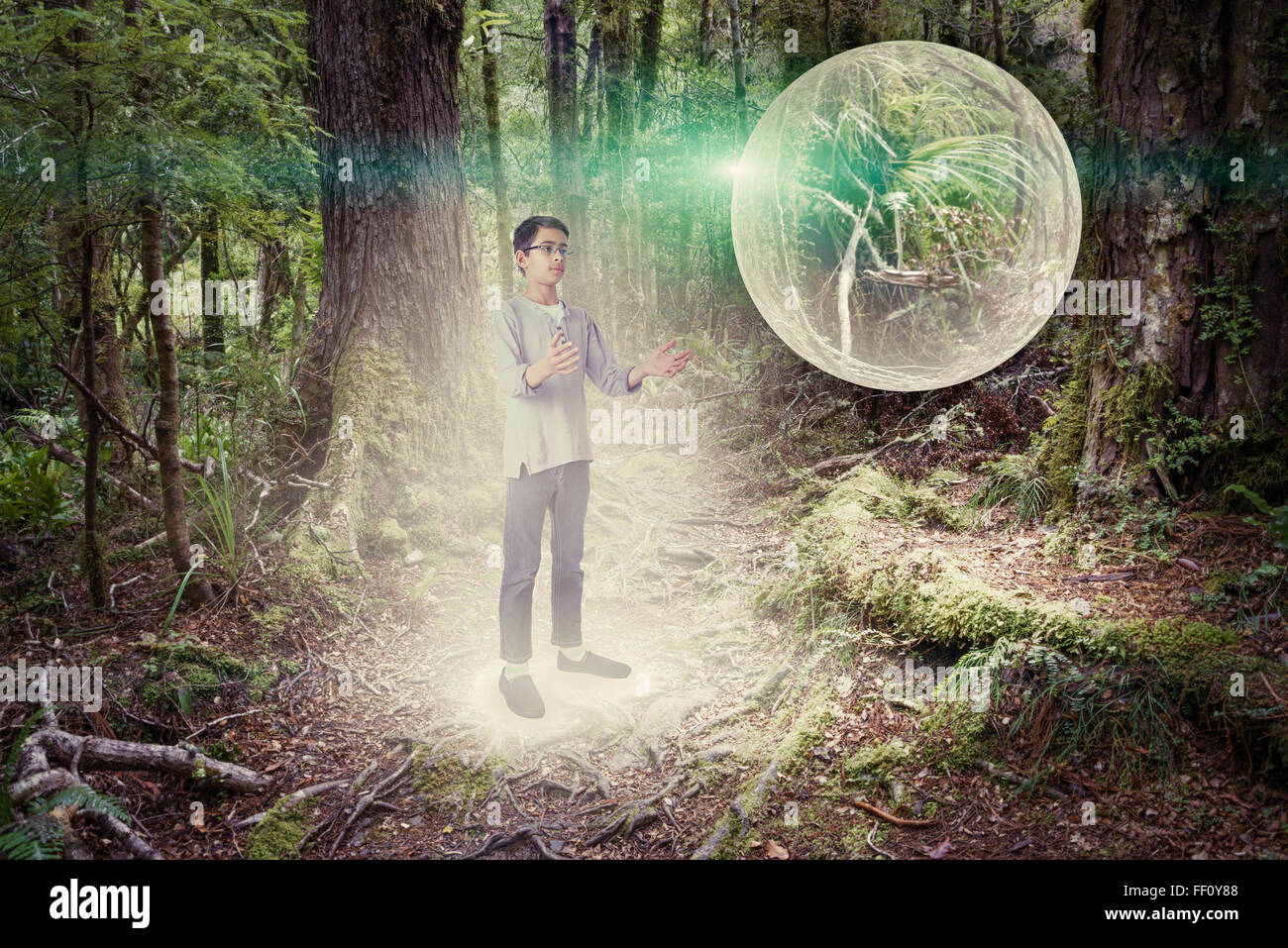 Mixed race boy admiring glowing orb in forest Stock Photo