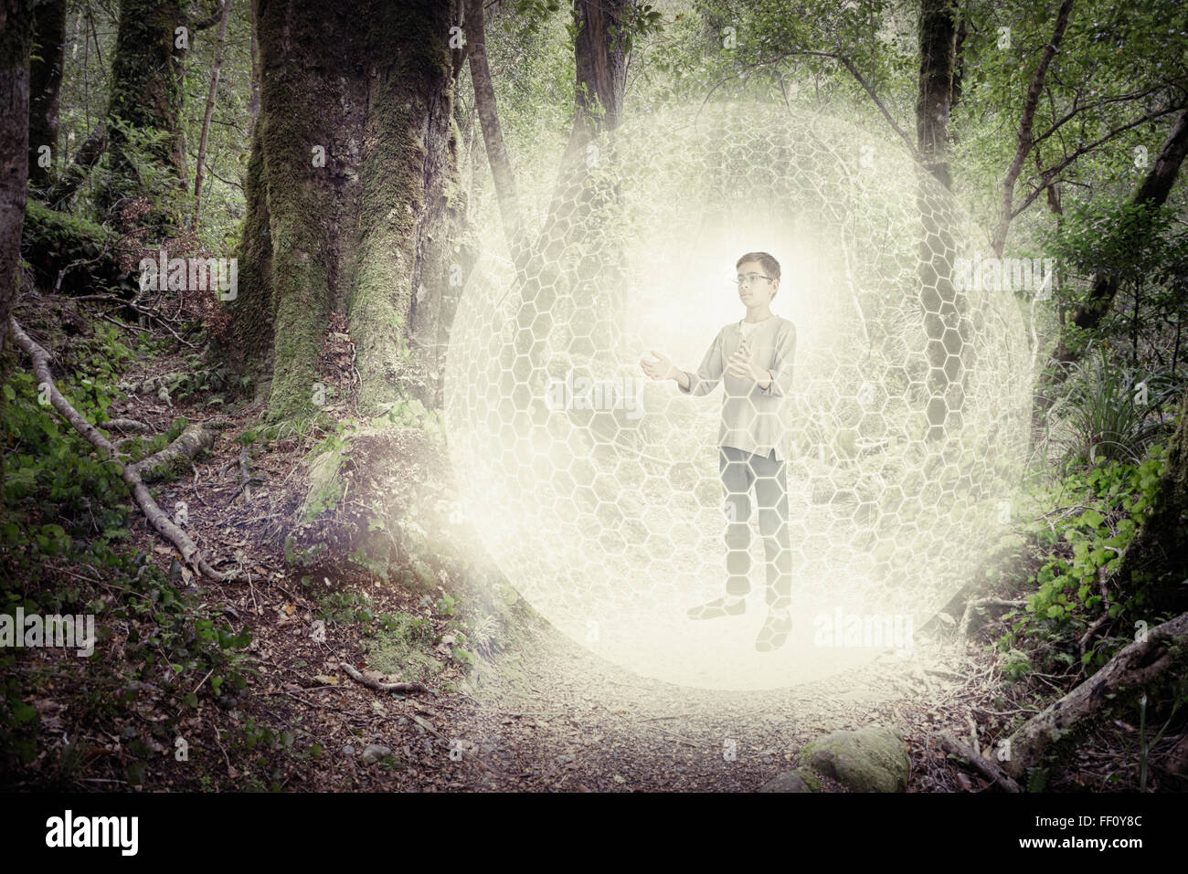 Mixed race boy in digital orb in forest Stock Photo