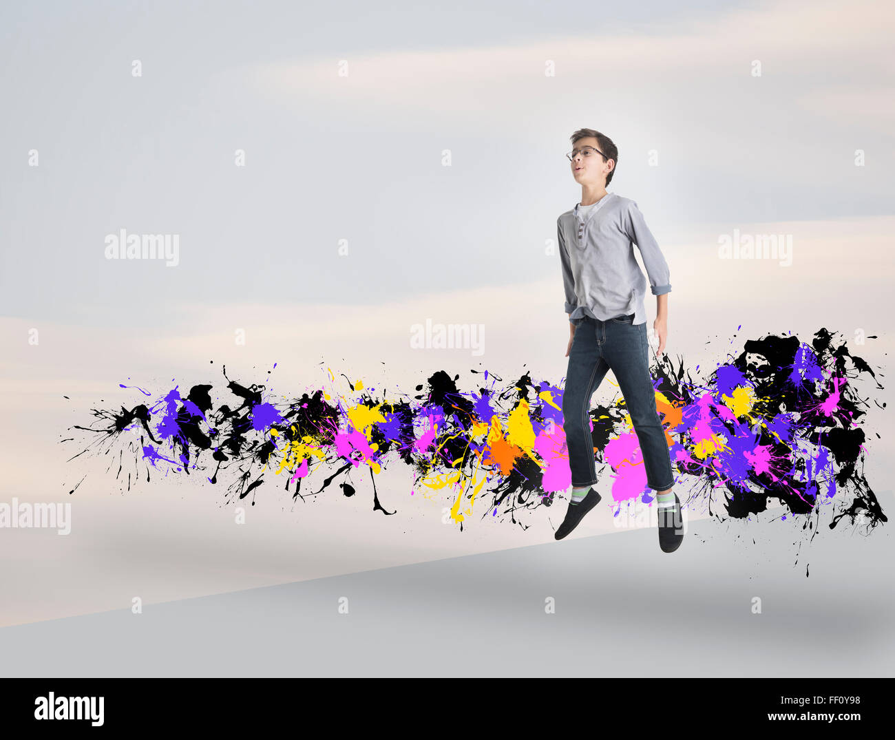 Mixed race boy jumping with paint splatters Stock Photo