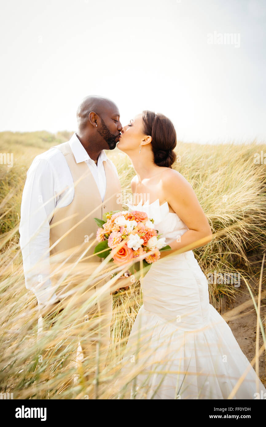 Newlywed couple kissing in grass Stock Photo