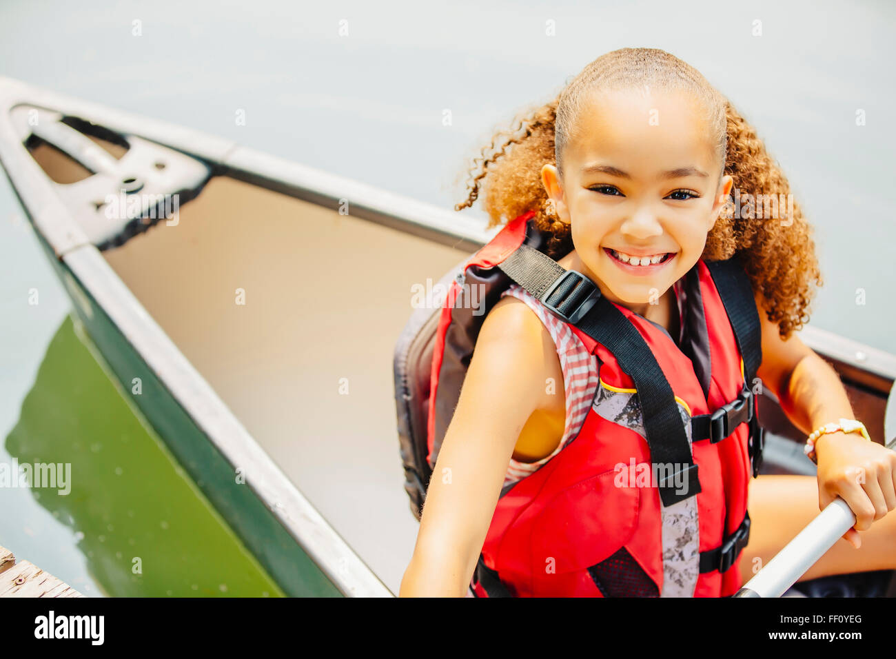 Mixed race girl smiling in canoe in lake Stock Photo