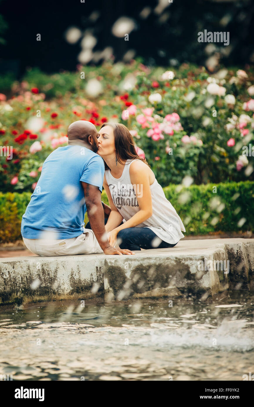 Couple kissing at fountain in garden Stock Photo