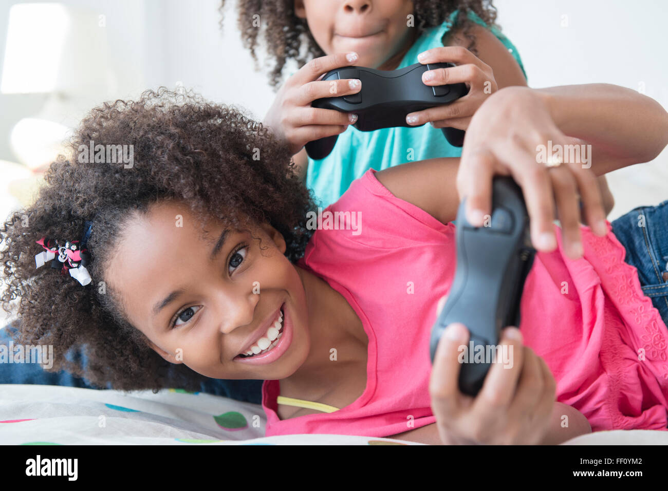 Mixed race sisters playing video games on bed Stock Photo Alamy