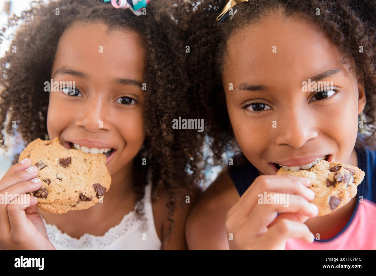 Mixed race sisters eating cookies Stock Photo