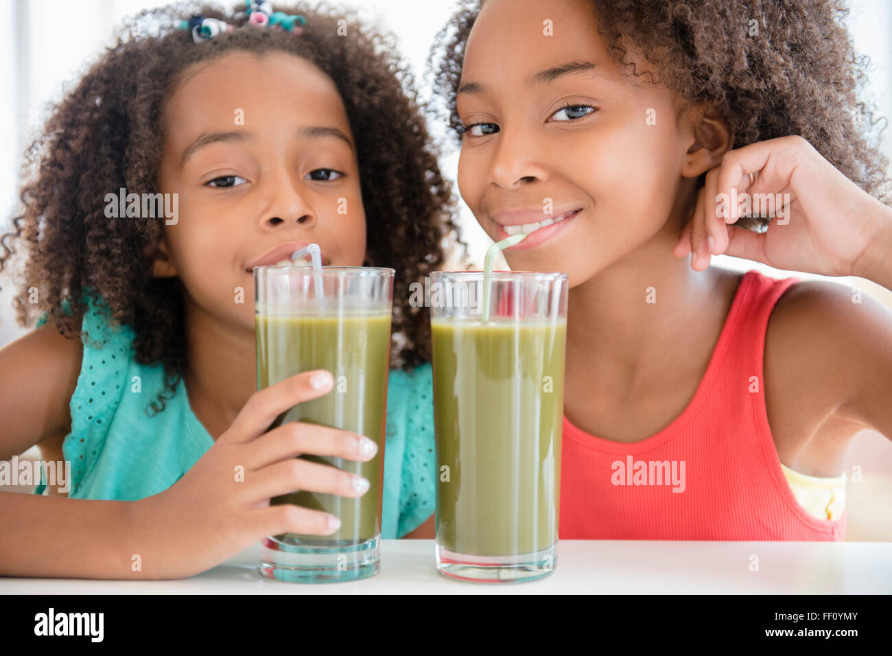 Mixed race sisters drinking healthy juice Stock Photo