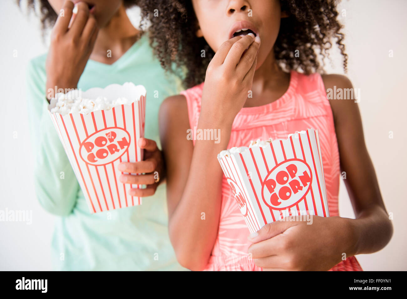 Mixed race sisters eating popcorn Stock Photo