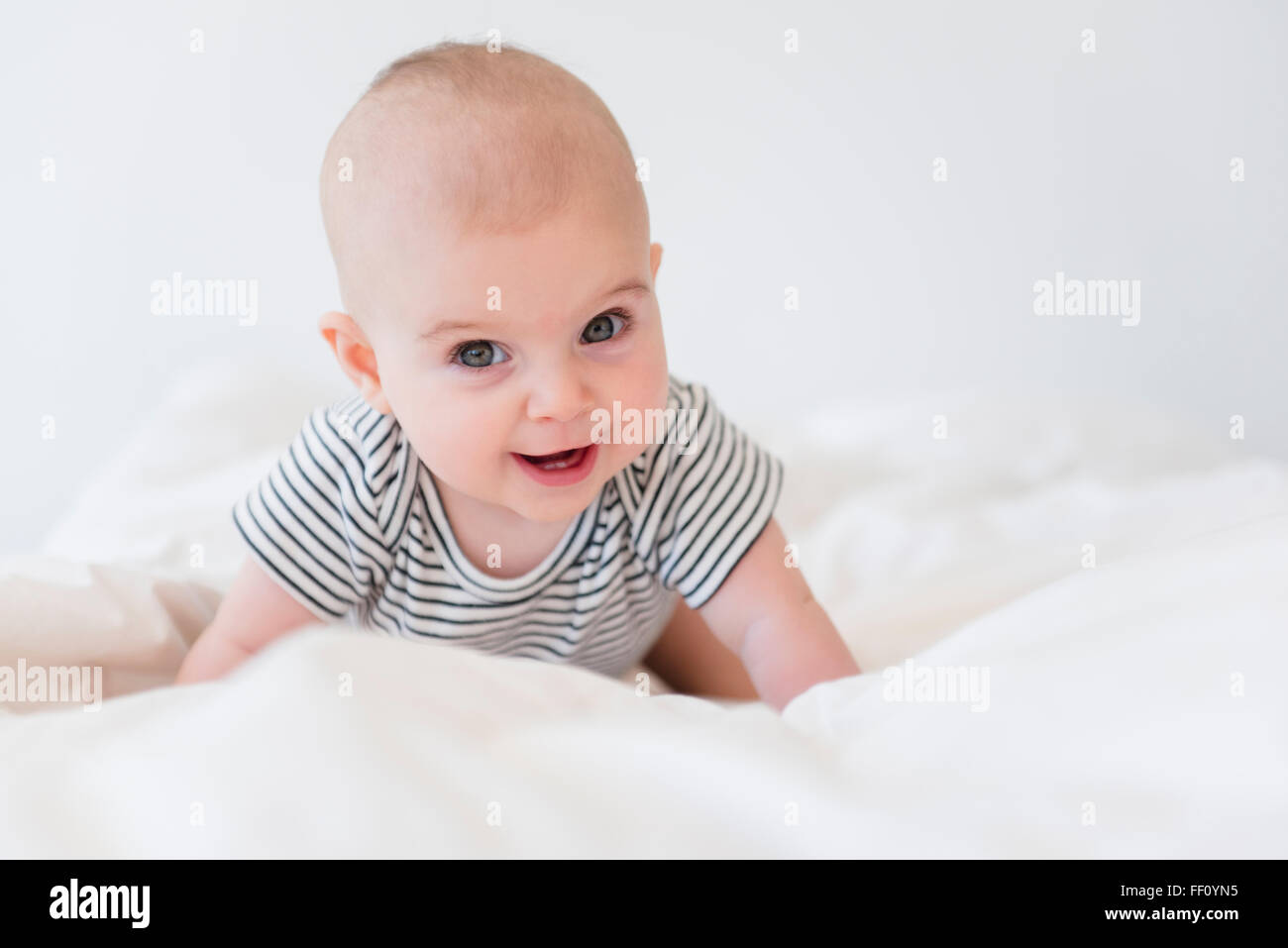 Caucasian baby girl crawling on bed Stock Photo