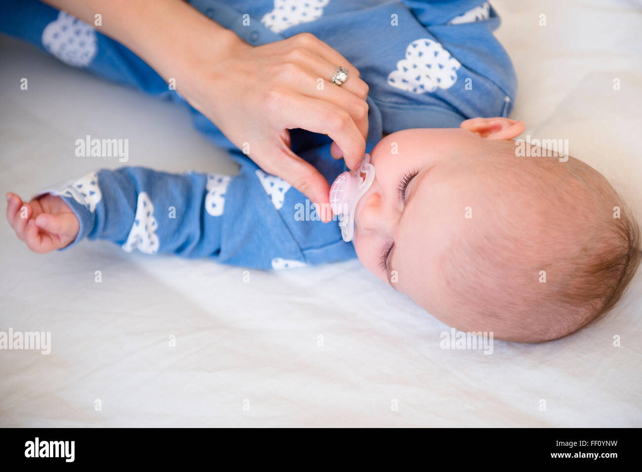 Caucasian mother giving baby daughter pacifier Stock Photo