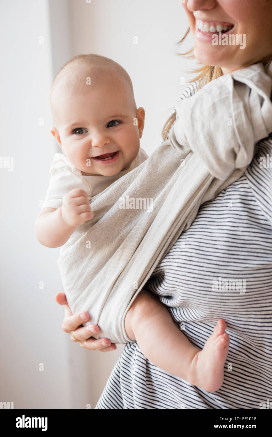 Caucasian mother holding baby daughter in sling Stock Photo