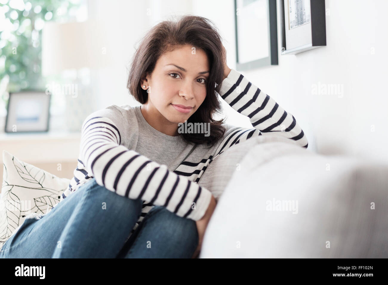 Mixed race woman sitting on sofa Stock Photo