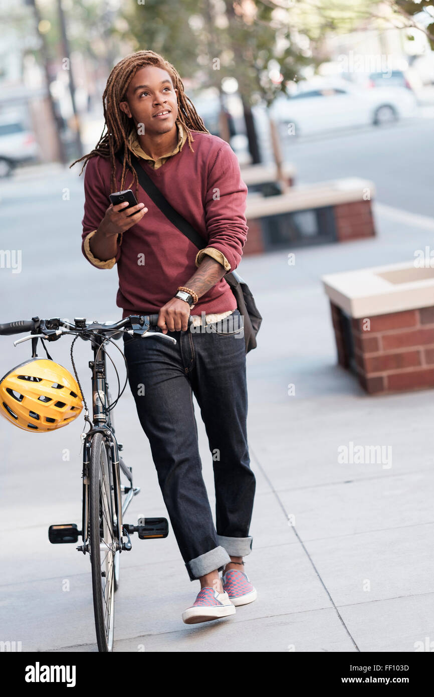 Mixed race man pushing bicycle outdoors Stock Photo
