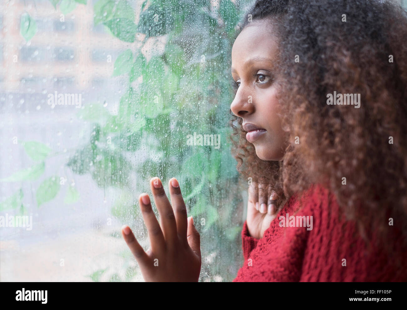 Black woman looking out rainy window Stock Photo