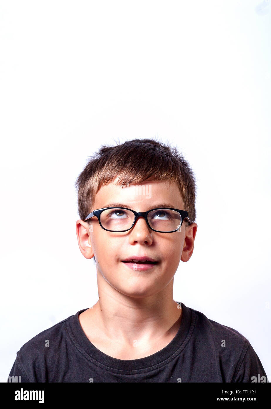 Thinking child portrait of a little boy age 11 in glasses thinking deeply about something looking up Stock Photo