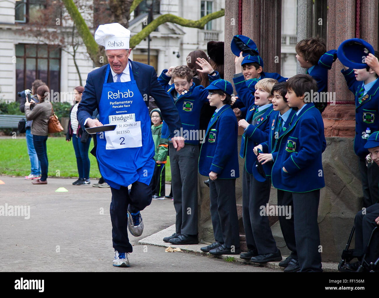 Westminster, London, United Kingdom. February 9th, 2016 - Lord St John of Bletso runs at the Parliamentary pancake race in aid of the disability charity, Rehab while a group of school children watch the race Credit:  Dinendra Haria/Alamy Live News Stock Photo