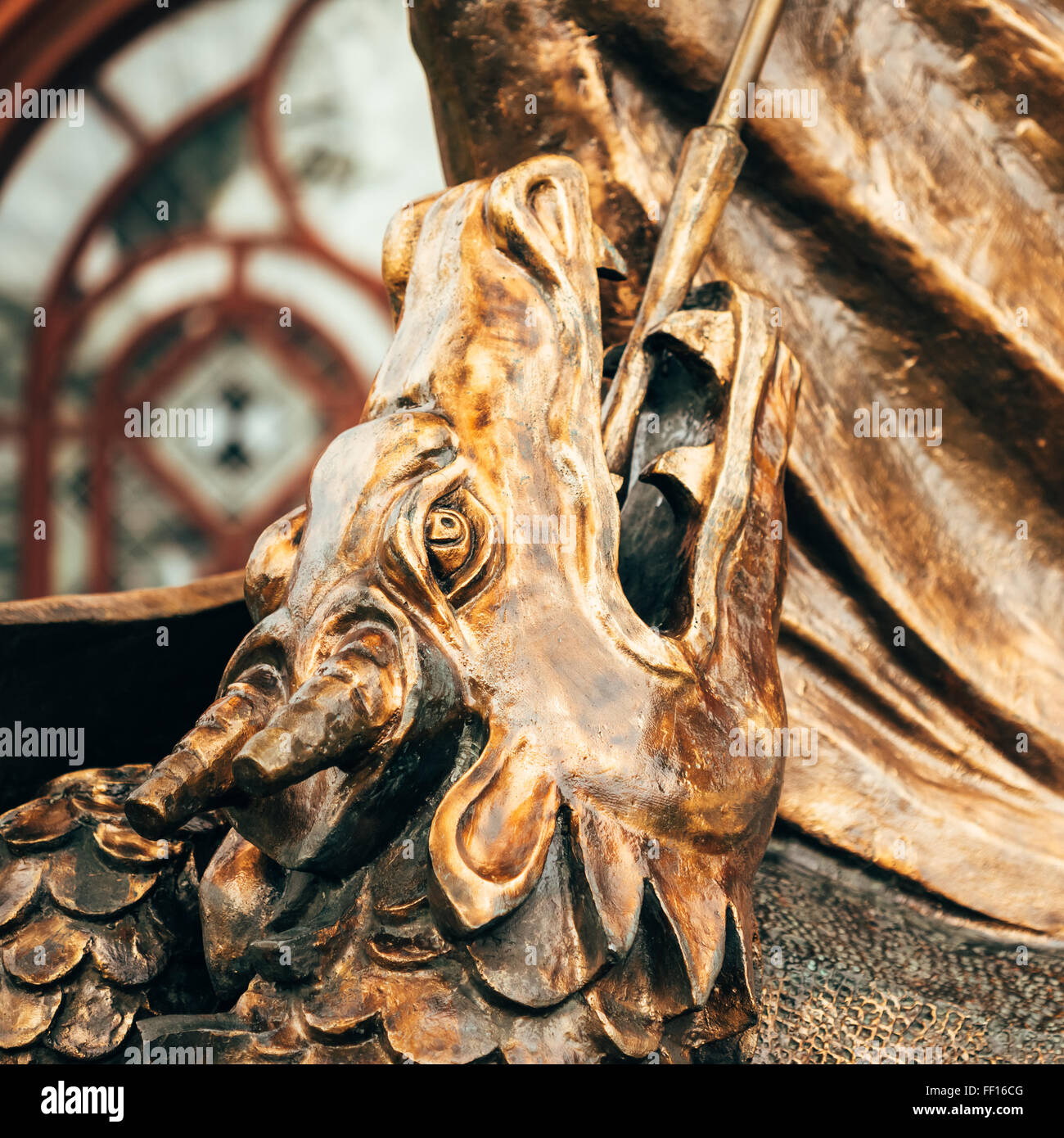 Close Up Detail Of Statue Of Archangel Michael Thrusting Spear Into Dragon Before Red Catholic Church Of St. Simon And St. Helen Stock Photo