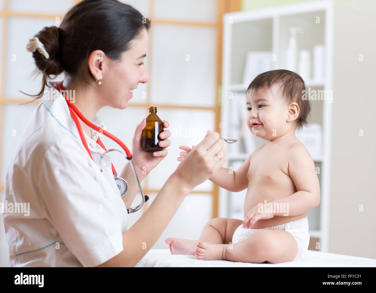 doctor giving medicament to kid with a spoon, hospital Stock Photo