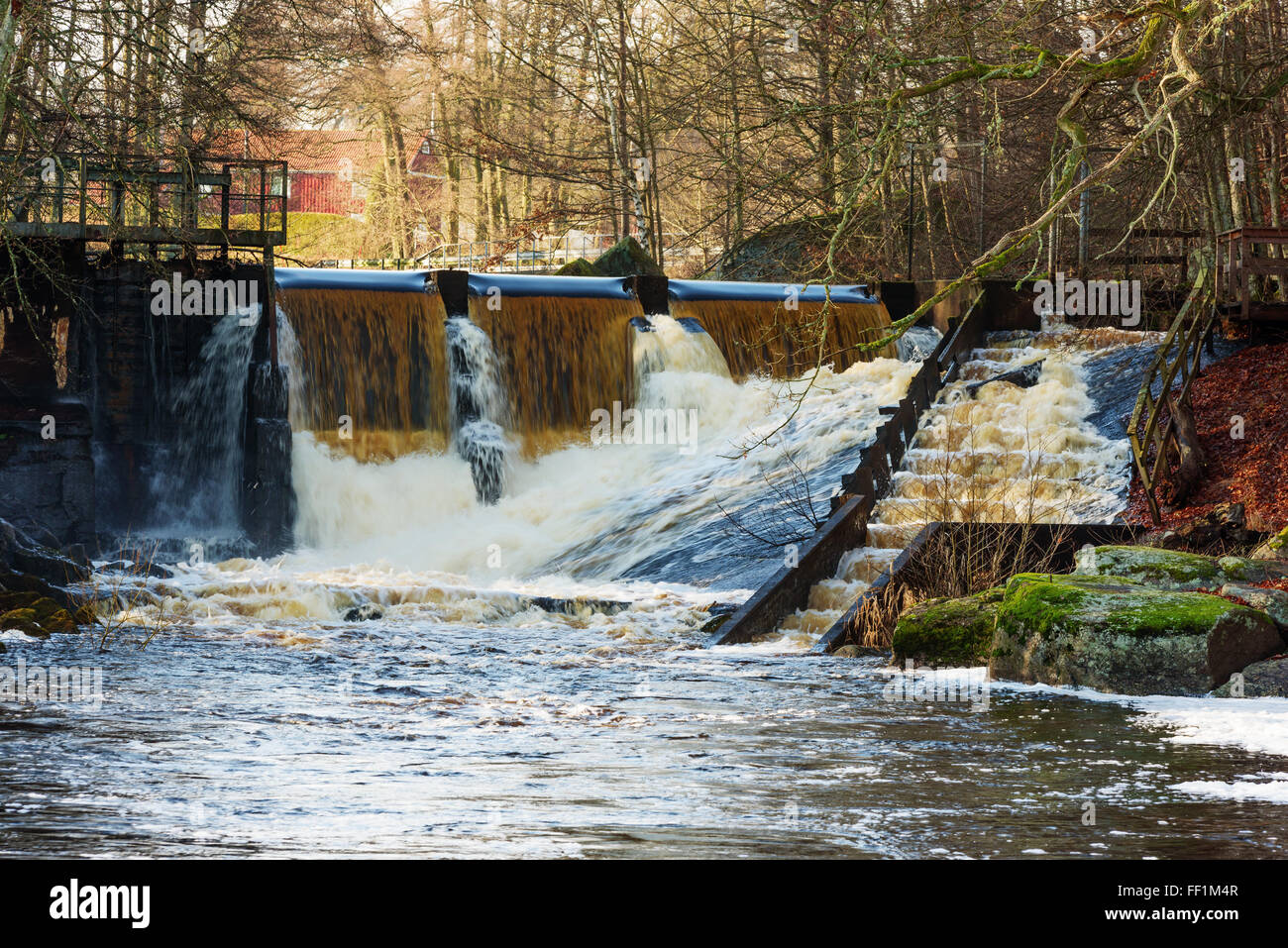A small dam with surrounding forestland. A fish ladder helps fish migrate. House visible in background. Snittingefallet in Bleki Stock Photo
